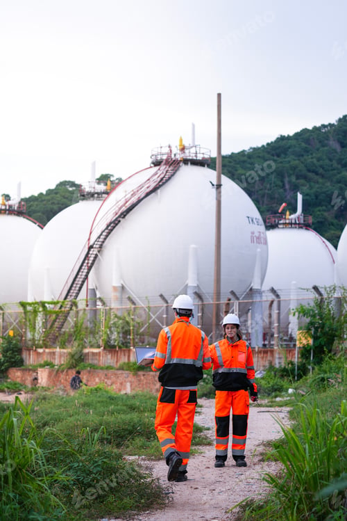 Preview: Two engineers in high-visibility safety gear and hard hats discuss project plans