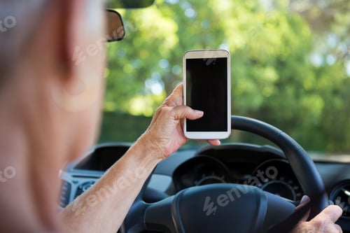 Preview: Senior woman using mobile phone while driving a car