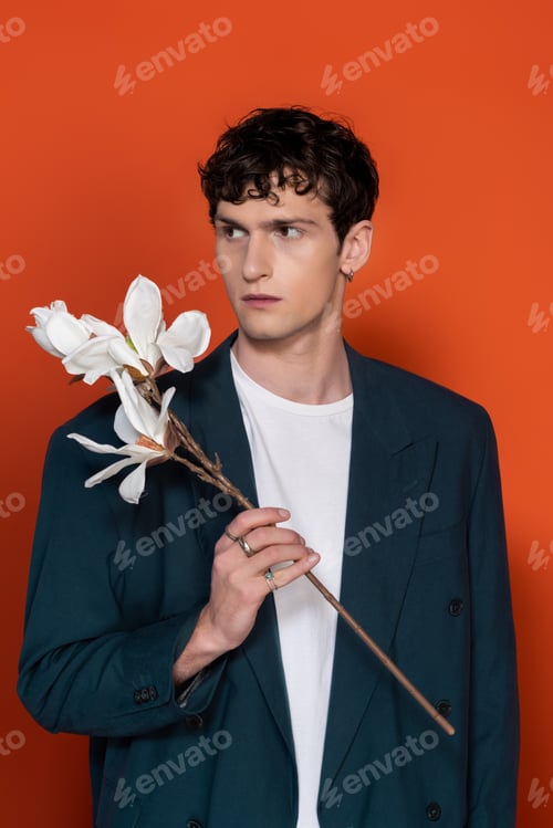 Preview: Man in blue jacket holding magnolia branch on red background