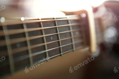 Preview: A man's hand on the fretboard of a guitar runs his fingers through the strings and clamps