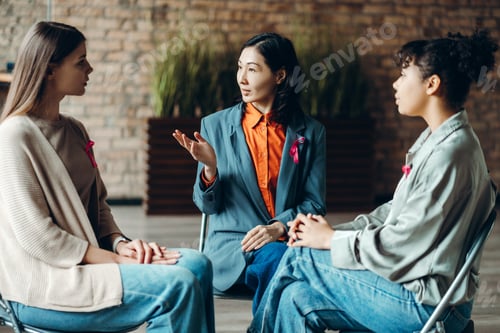 Preview: Doctor explaining breast cancer awareness to women during meeting