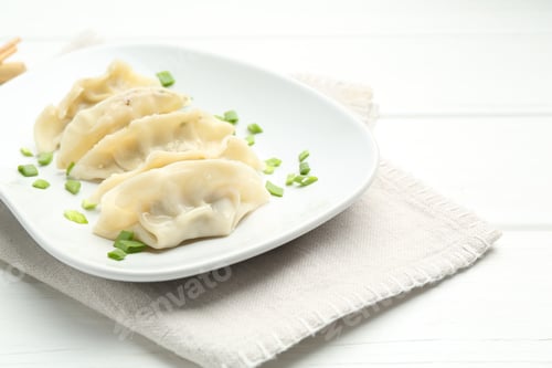 Preview: Tasty boiled gyoza (dumplings) with green onion on white wooden table, closeup. Space for text