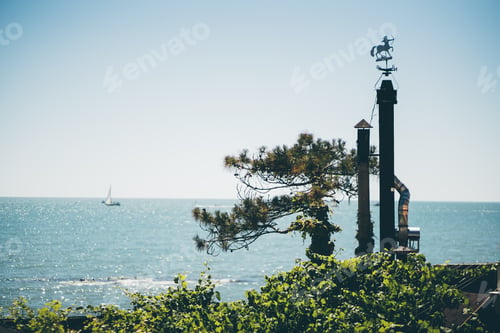 Preview: Two chimney flues with weather-vane on seashore