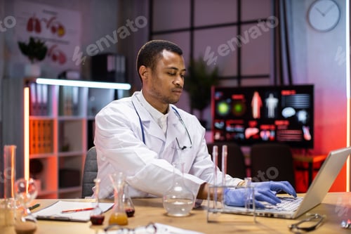 Preview: Male african american scientist testing experiment in science lab using laptop computer.