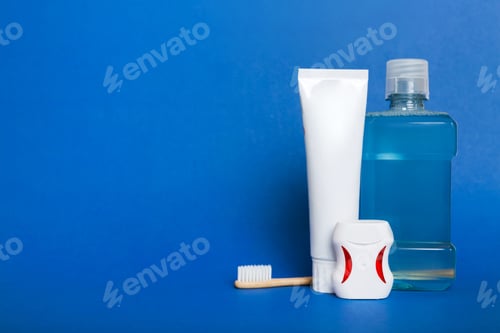 Preview: Mouthwash and other oral hygiene products on colored table top view with copy space.