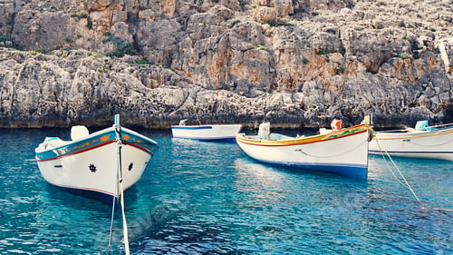 Preview: Empty traditional Maltese boats Luzzu in Blue Grotto Bay. Tourism low season concept