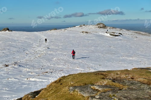 Preview: Hiker walking on the mountain covered by snow in Dartmoor National Park, UK