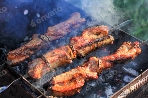 Preview: Barbecue skewers with juicy meat cooking in open air in summer. Food background.