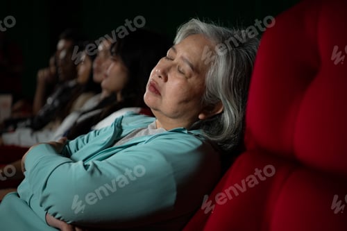 Preview: Senior woman falls asleep while watching movie in cinema and popcorn in hand,