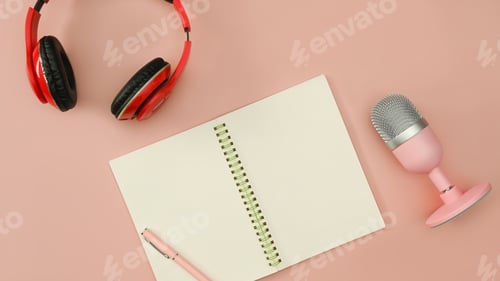 Preview: Top view composition with microphone for podcasts, notepad and headphones on pink background.