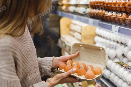 Preview: Woman chooses chicken eggs in a farm food store. Food consumption, Easter