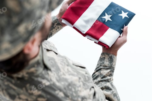 Preview: partial view of male soldier in military uniform with american flag in hands