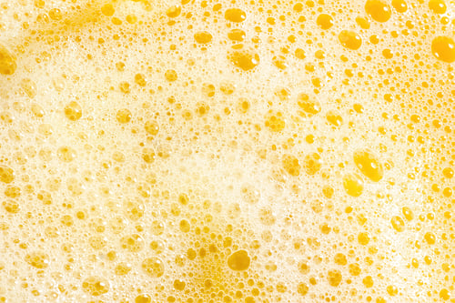 Preview: Closeup of orange juice foam, top view. Splash of fresh sweet orange, mango, fruit juice.