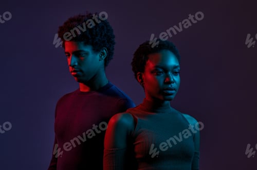 Preview: Young man and woman in neon light over dark background