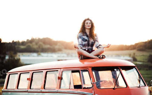 Preview: A young girl on a roadtrip through countryside, sitting on the roof of minivan doing yoga.