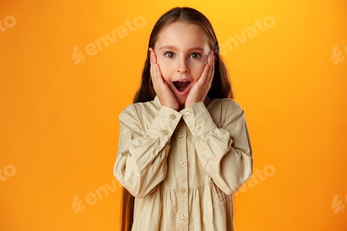 Preview: Surprised teenage girl over yellow background in studio
