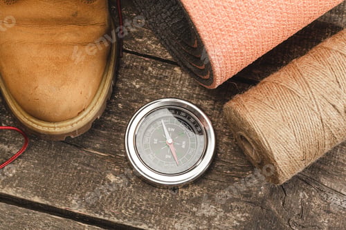 Preview: Compass surrounded by mountain gear tools on wooden background