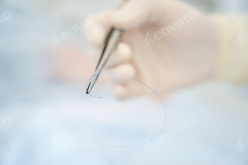 Preview: Surgeon holds in his hand a surgical needle