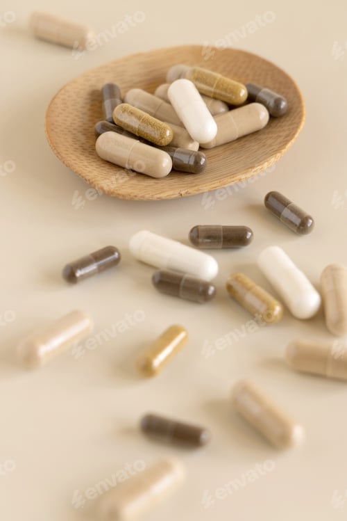 Preview: Mix of medical capsules in a bowl on light beige close up. Taking dietary supplements
