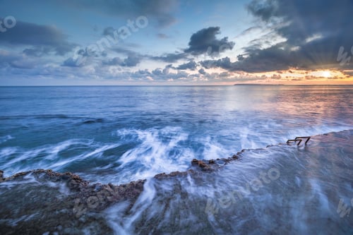 Aperçu: Sun rising over waving sea