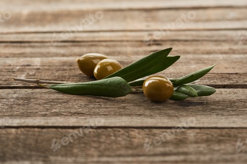 Preview: olive tree branch and green olives on wooden surface