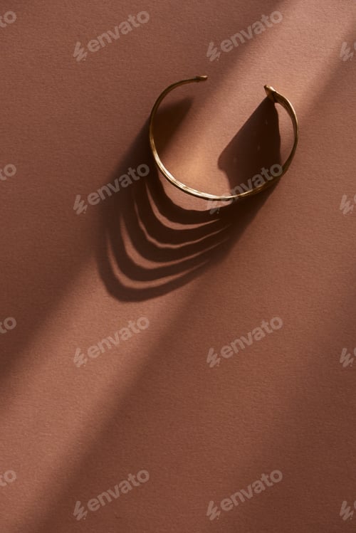 Visualização: top view of beautiful luxury bracelet on brown surface with sunlight