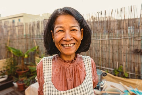 Preview: Happy Thai woman having fun smiling in front of camera while preparing food recipe at house patio