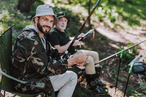 Preview: Positive Smiling Bearded Man Enjoying Fishing While Resting With His Father