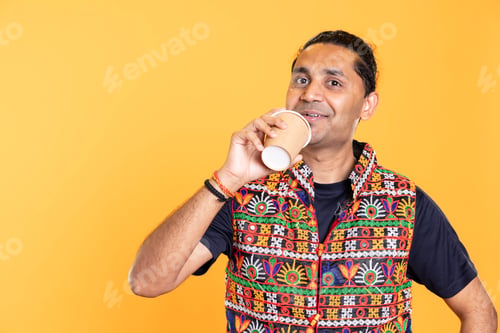 Preview: Smiling person with colorful vest drinking hot beverage, studio background