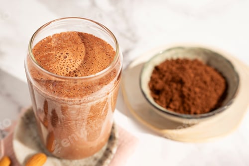 Preview: Chocolate protein shake, presented in a glass beside it, a bowl of cocoa.