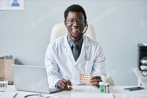 Preview: Smiling African American doctor wearing headset at workplace in office