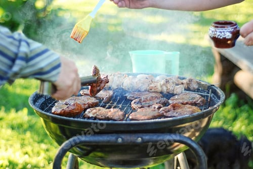Preview: Appetising steaks and kebabs are grilled in the backyard, mens hands are cooking meat with the sauce