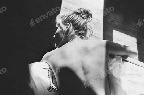Preview: Young naked woman lying on the bed at home, enjoying the sun