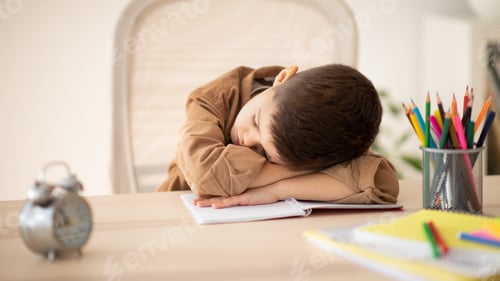 Vista previa: Bored unhappy tired caucasian little child sleeping at table, suffering from homework in room