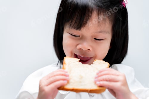 Preview: Cute baby girl eats bread on white background. Child enjoy and biting food.