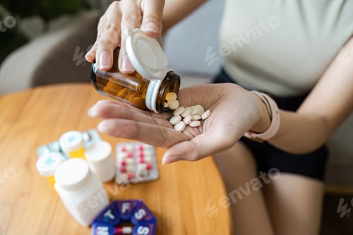 Preview: Close-up of a Person Pouring Pills from a Bottle into Their Hand with Various Medications on a
