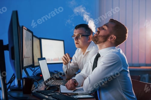 Preview: Man is smoking. Two stock traders working in the office with exchange technology