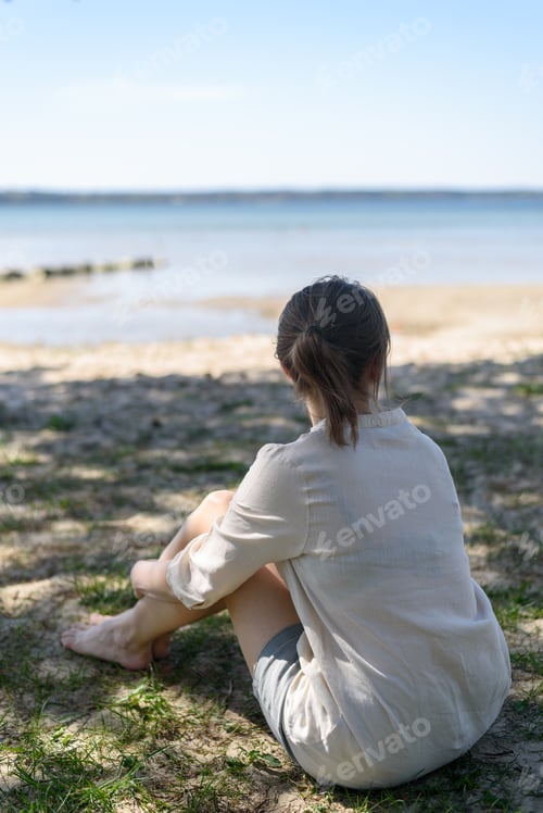Preview: Woman sitting between trees and looking to sea
