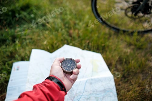 Preview: Unrecognizable cyclist using compass over map.