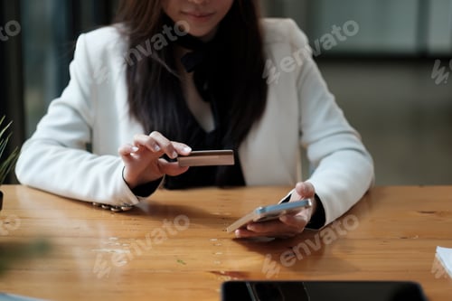 Preview: Young woman holding credit card and using smart phone for online shopping. Online payment shopping