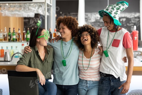 Preview: Diverse group of friends celebrating st patrick's day embracing and laughing at a bar