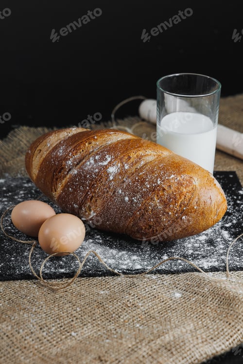Preview: Delicious round rye bread with milk and eggs on a dark background. Crispy fresh bread.