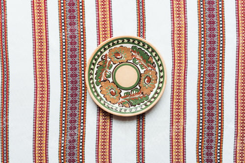 Preview: top view of plate with traditional ornament and embroidered towel on background