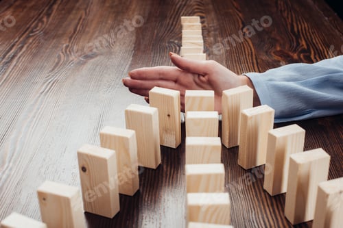 Preview: selective focus of woman preventing wooden blocks from falling