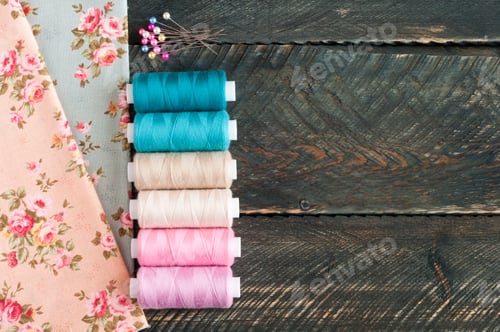 Preview: Fabrics, spools of thread and pins on old wooden background. Sewing accessories