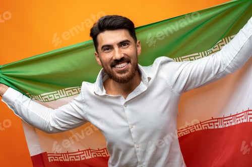 Preview: Portrait of a young casual man holding flag of Iran against orange background