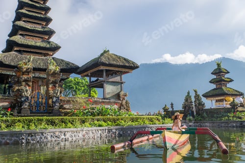 Preview: Young woman traveler paddling on a wooden boat at Pura Ulun Danu Bratan