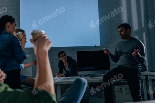 Preview: cropped image of people in office at nighttime with coffee cups