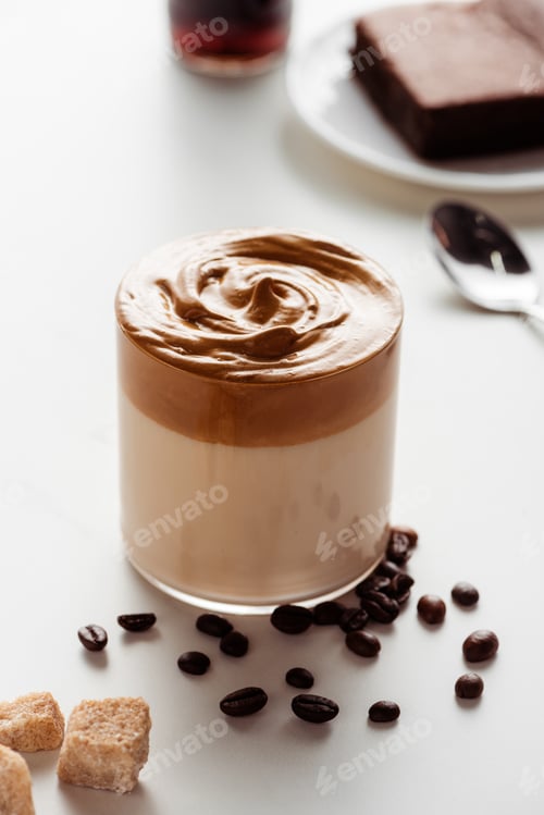 Preview: Delicious Dalgona Coffee in Glass Near Coffee Beans And Brown Sugar on White Background