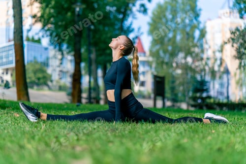 Preview: A young beautiful girl sits on the splits and does stretching after training in morning in the park